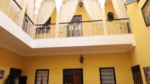 A spacious courtyard with a fountain, multiple seating areas, and a balcony with decorative railings. - 66 Av. Imam El Ghazali (Marrakech)