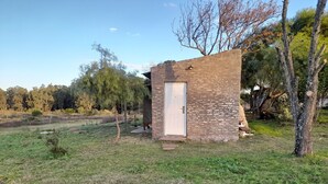 A small brick structure with a white door, surrounded by grass and trees.