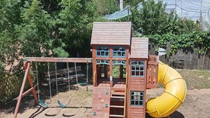 A wooden play structure with a slide and climbing steps.