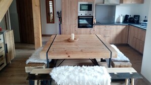 A modern kitchen with wooden cabinets, a built-in oven, and a dining table with a white fluffy rug.