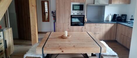 A modern kitchen with wooden cabinets, a built-in oven, and a dining table with a white fluffy rug.