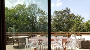An outdoor deck with a wooden table and chairs, surrounded by a wooden railing.