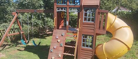 Una estructura de madera para jugar con un tobogán y escalones para trepar.