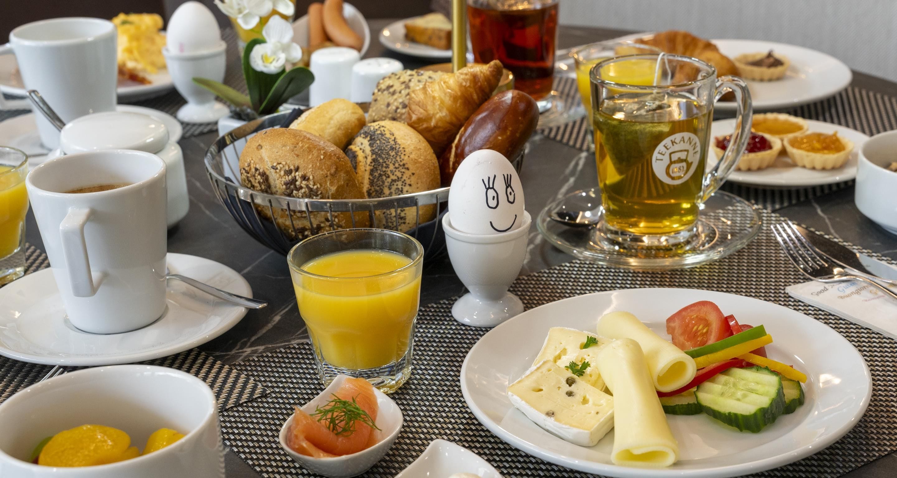 Un'impostazione per la colazione con diversi cibi, un teiera e una tazza di tè.
