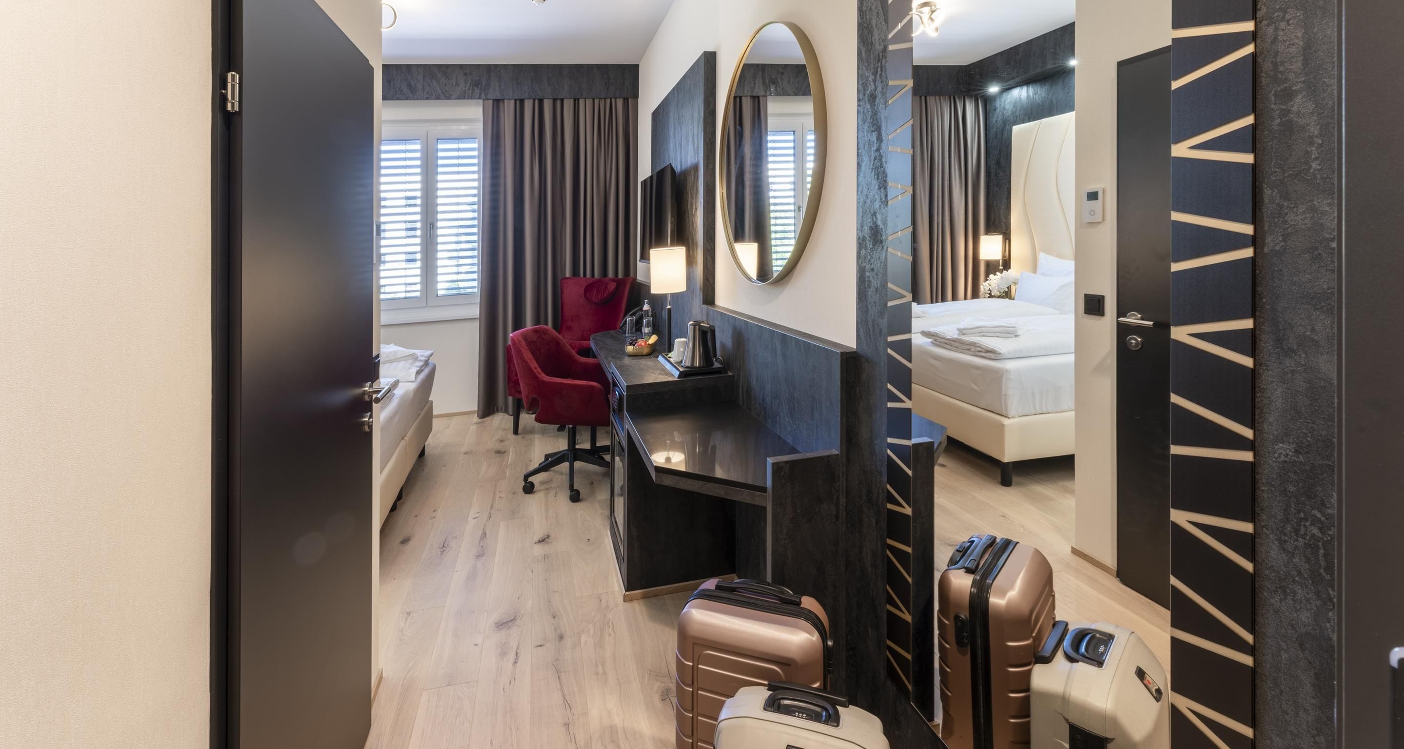 Una habitación de hotel con una cama, un escritorio, una silla, un espejo y un armario.