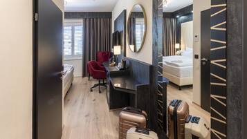 Una habitación de hotel con una cama, un escritorio, una silla, un espejo y un armario.