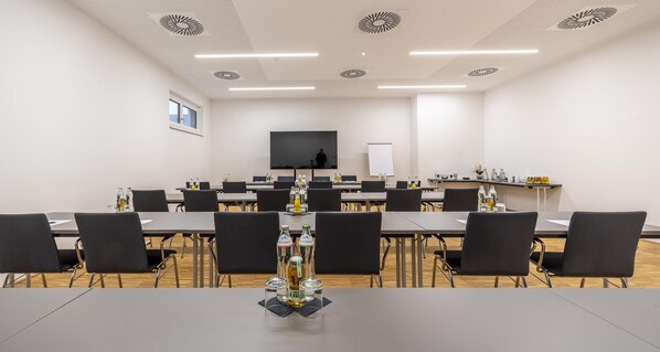A conference room with a long table, chairs, a whiteboard, and a television screen. - PLAZA INN Wiener Neustadt, BW Signature Collection (Wiener Neustadt)