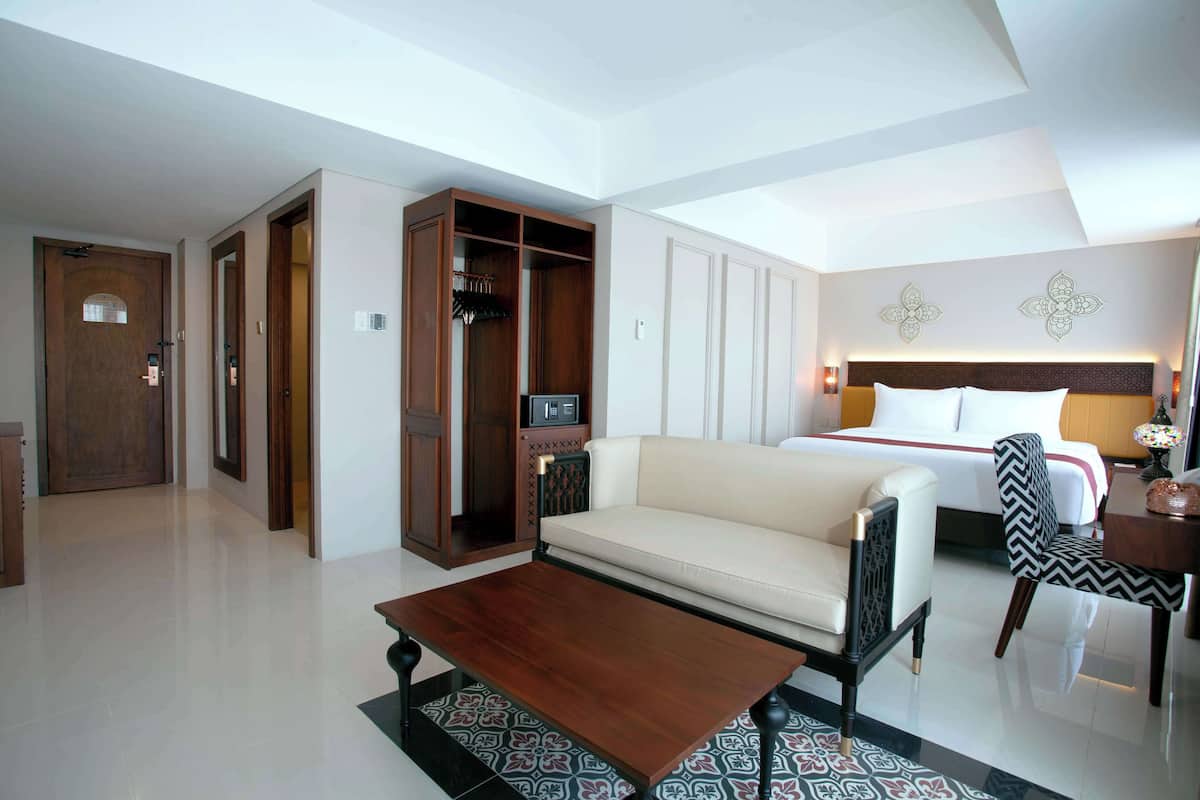 Une chambre d’hôtel comprenant un lit, un canapé, une table basse, une armoire et un bureau.