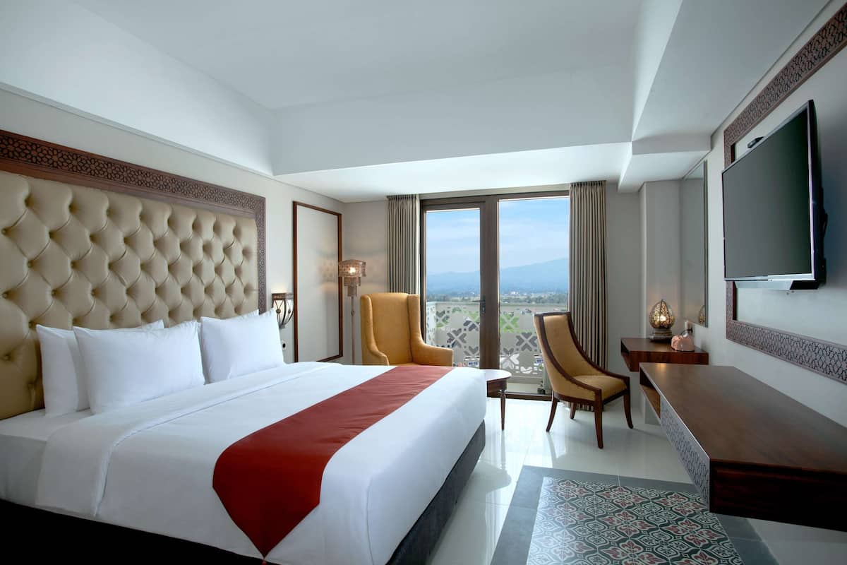 Une chambre d’hôtel avec un grand lit, une télévision, un bureau et une chaise.