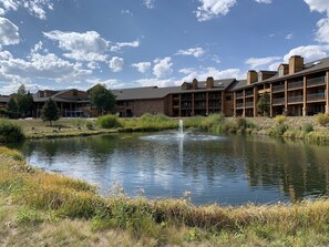 A hotel with multiple floors, outdoor seating areas, and a pond with a fountain.