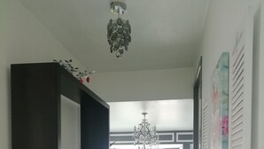 Un pasillo con un mueble de madera oscura, un candelabro y una cama con edredón estampado de flores.