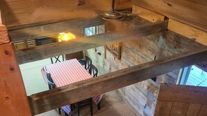 Un interior de madera con techo alto, una mesa con mantel a cuadros y una lámpara.
