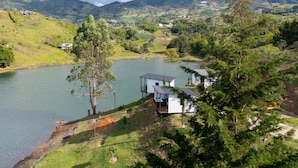 A lakeside property with a house overlooking the water, surrounded by greenery and hills.