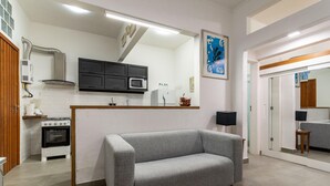 Una cocina compacta con un sofá gris, un microondas y una estufa.