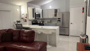 Una cocina moderna con armarios blancos, electrodomésticos de acero inoxidable y una isla central con taburetes de bar.