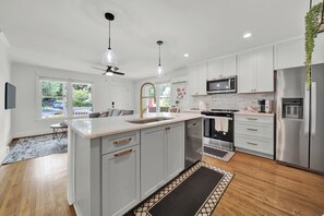 A modern kitchen with white cabinets, stainless steel appliances, and a large island with a sink.