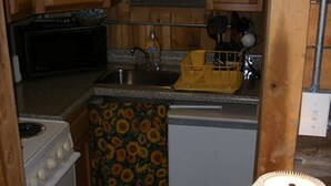 A kitchen with wooden cabinets, a microwave, a sink, and a stove.