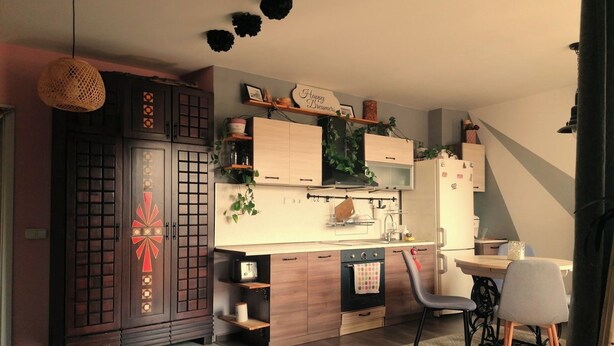 A modern kitchen with wooden cabinets, a built-in oven, and a dining area with a round table and two chairs.