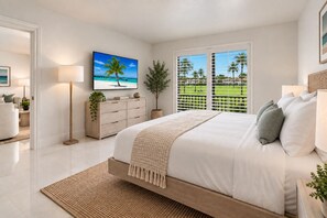 Un dormitorio con una cama grande, televisión, planta y vista a un campo de golf por la ventana.