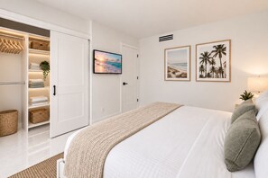 Ein Schlafzimmer mit Bett, Kleiderschrank, Fernseher und Wandbildern.