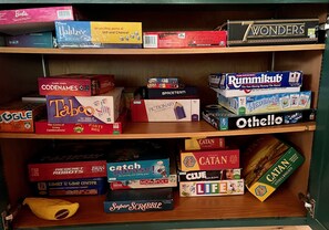 Une étagère contenant divers jeux de société, notamment Codenames, Taboo et Catan.
