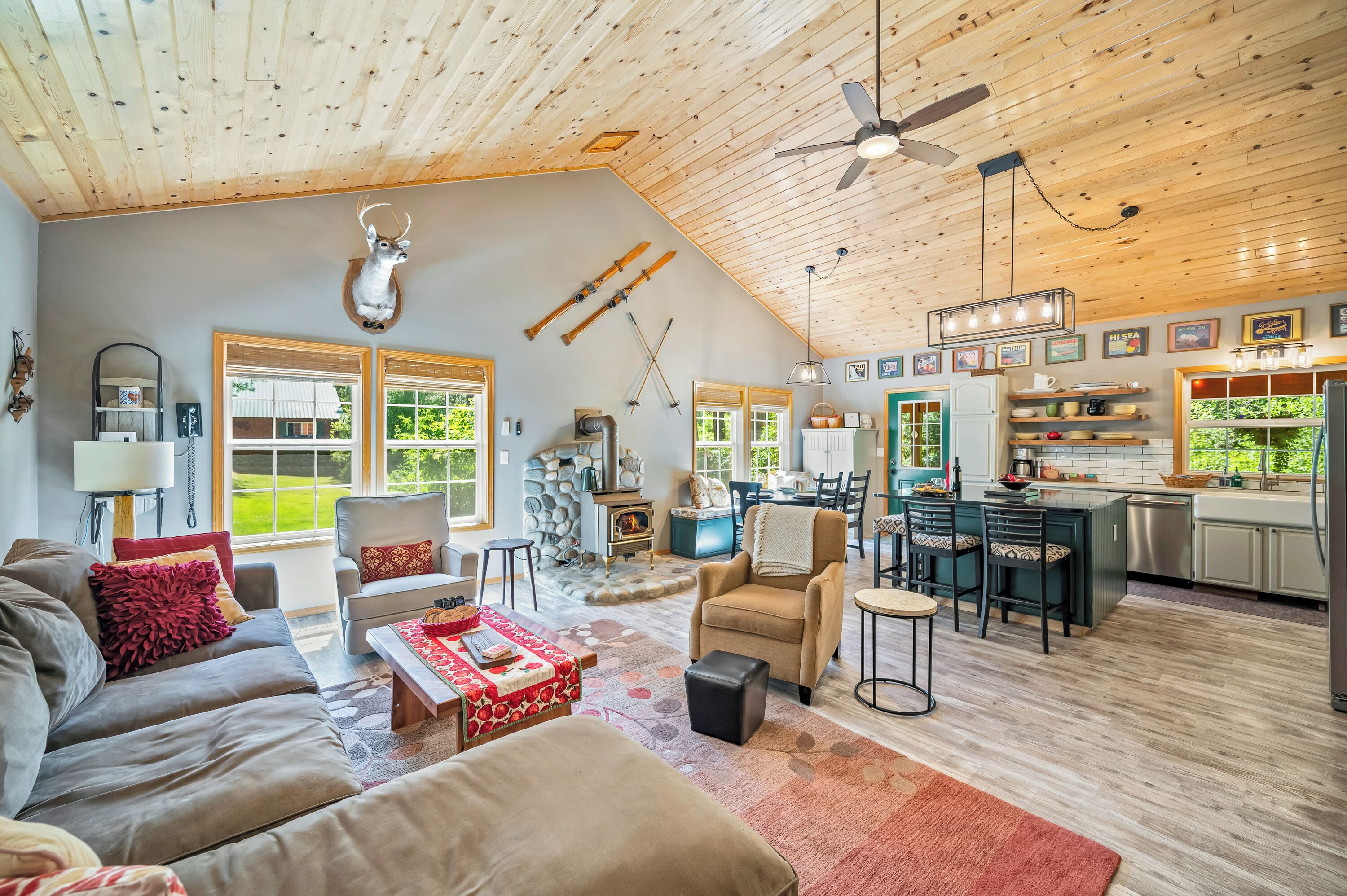 A spacious living area with a fireplace, wooden ceiling, and a kitchen with a large island.