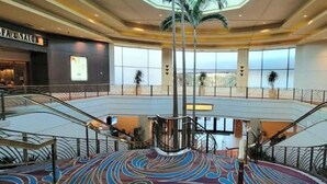 A spacious atrium with a central circular area, multiple levels connected by escalators, and a view of the outside through large windows.