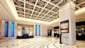 A spacious lobby with a high ceiling, a central seating area, and a patterned floor.
