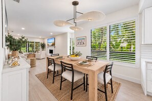 A modern dining area with a wooden table, chairs, and a central light fixture.