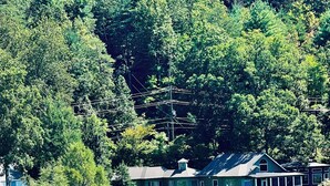 A lakeside property with a dock, a small boat, and a beach area with umbrellas and lounge chairs. - Beautiful NEW 5 br 4 bath Log cabin with PRIVATE HOT TUB overlooking Lake Lure (Lake Lure)