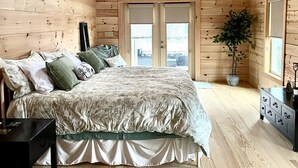 A wooden cabin bedroom with a bed, dresser, nightstand, ceiling fan, and a potted plant. - Beautiful NEW 5 br 4 bath Log cabin with PRIVATE HOT TUB overlooking Lake Lure (Lake Lure)