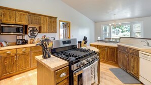 A kitchen with wooden cabinets, a stainless steel stove, a microwave, and a sink.