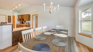 A dining area with a wooden table, white chairs, and a chandelier.