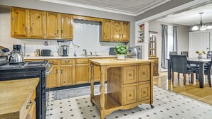 Uma cozinha com armários de madeira, fogão e área de jantar com mesa e cadeiras.