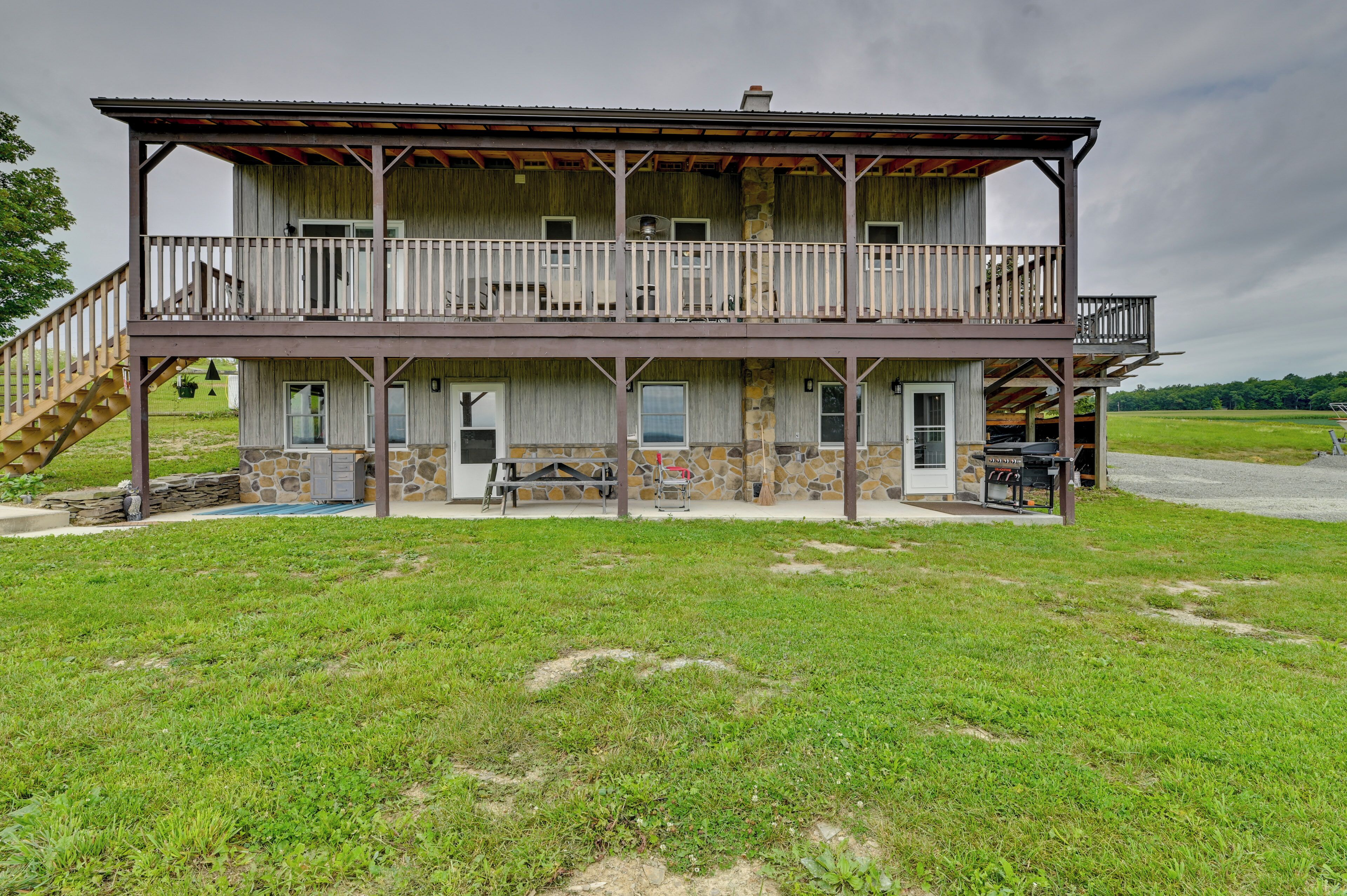 A two-story wooden building with a balcony, a staircase, and a stone foundation.