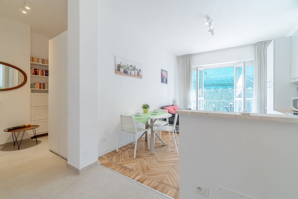 Una sala moderna con comedor, un ventanal con vistas y una estantería.