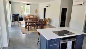 A modern kitchen with a central island, built-in oven, and a dining area with a sofa and table.