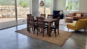 A spacious living room with a dining area, large windows, a sofa, and a yellow armchair.