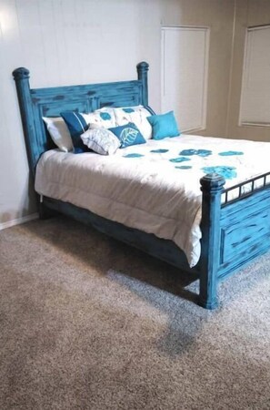 Un dormitorio con un cabecero de madera azul, una colcha blanca y almohadas azules y blancas.