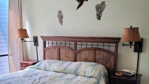 Un dormitorio con cama, mesita de noche, cómoda y decoración en la pared.