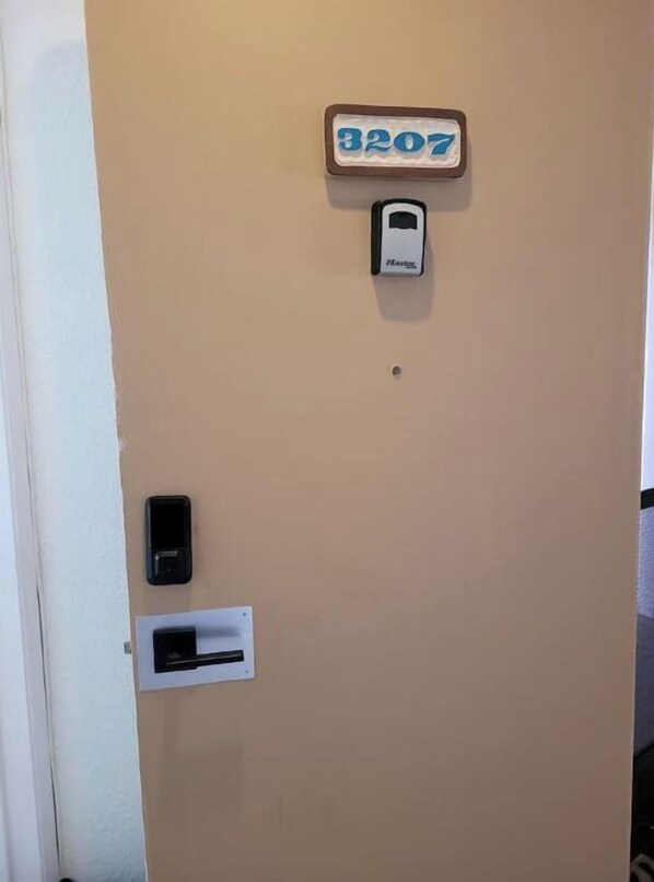 Une porte dotée d’une fente pour le courrier, d’un lecteur de cartes magnétiques et d’un panneau indiquant le numéro de la porte.