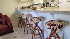 Una cocina con barra, que incluye taburetes de madera con cojines estampados.