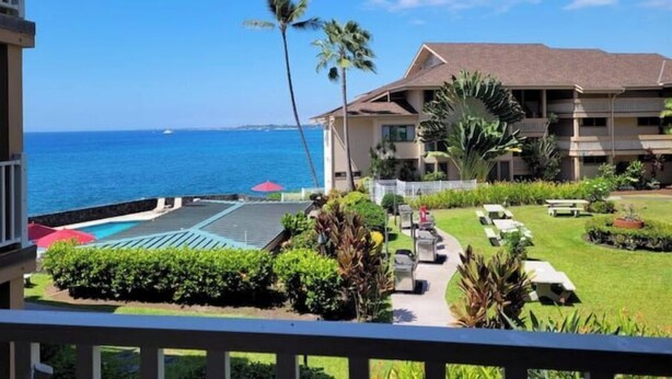 Un hotel con piscina, palmeras y vista al océano.