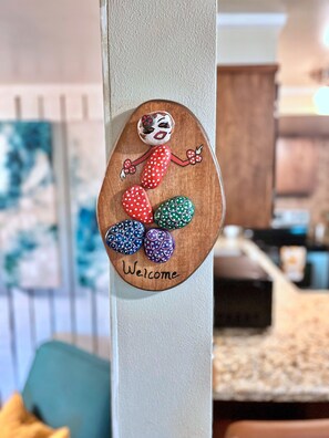 Un letrero de madera con huevos pintados y la palabra 'Welcome' en una puerta.