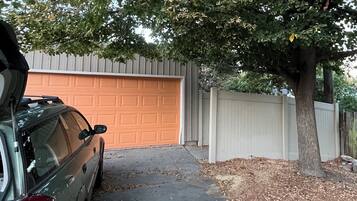 A residential driveway with a parked car, a garage door, and a tree.
