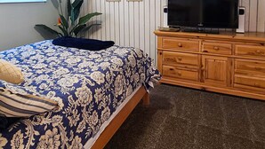 A bedroom with a bed, a television, a clock, and a plant. - 3BR Near SLC & Airport +Game Room | Basement level (West Valley City)