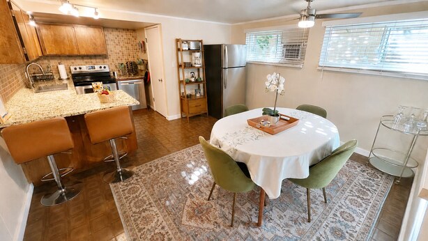 A kitchen with a dining area, including a round table with chairs, a rug, and a refrigerator. - 3BR Near SLC & Airport +Game Room | Basement level (West Valley City)