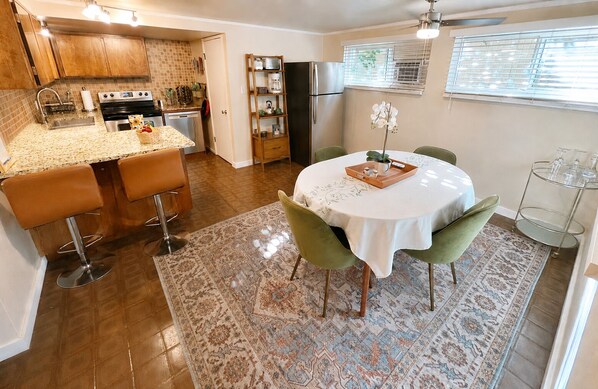 Una cocina con comedor, que incluye una mesa redonda con sillas, una alfombra y un refrigerador.