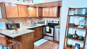 A kitchen with wooden cabinets, a microwave, a stove, a sink, and a coffee maker. - 3BR Near SLC & Airport +Game Room | Basement level (West Valley City)