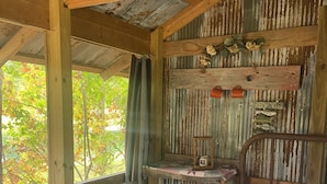 A rustic cabin with a wooden bed, a small table, and a shelf with decorative items.